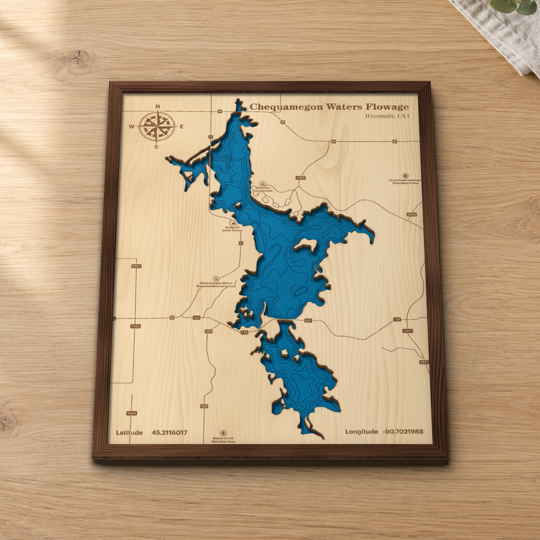 Chequamegon Waters Flowage wood map lying flat on a wooden tabletop, showing the flowage depth contours engraved in