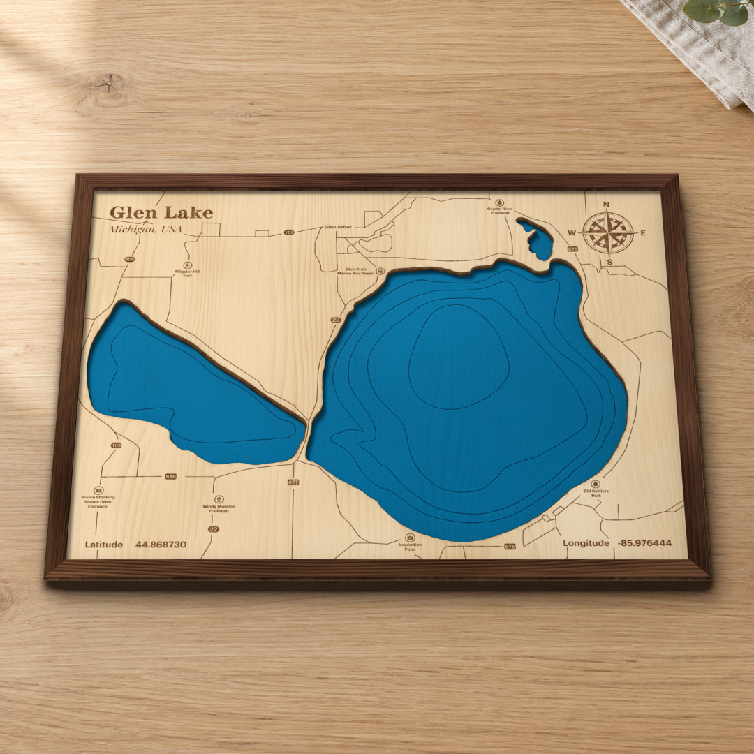 Glen Lake wood map lying flat on a wooden tabletop, showing the depth contours of Big and Little Glen and the narrows engraved in