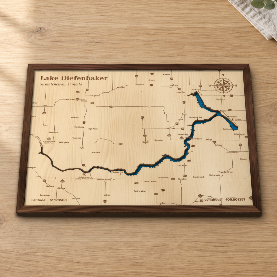 Lake Diefenbaker wood map lying flat on a wooden tabletop, showing the reservoir's depth contours with Elbow, Riverhurst and the prairie towns around the lake engraved in