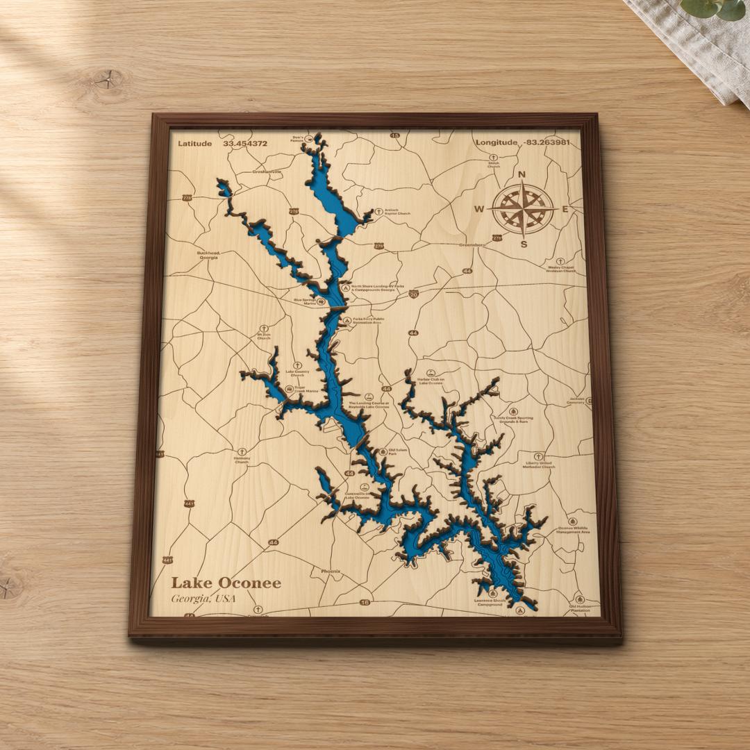 Lake Oconee wood map lying flat on a wooden tabletop, showing the lake's coves and depth contours with Greensboro, Reynolds Lake Oconee and Sugar Creek Marina engraved in