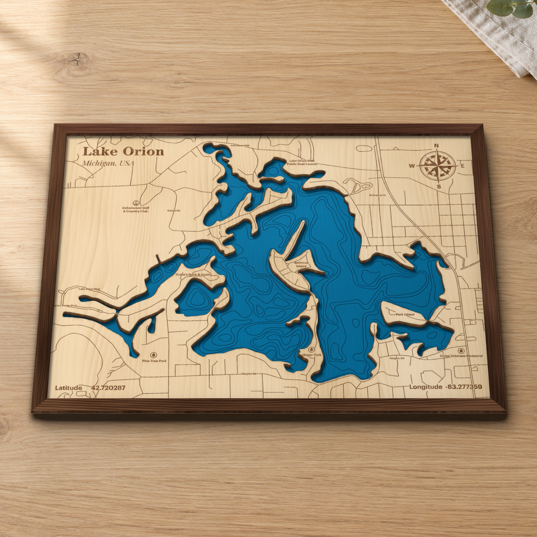 Lake Orion wood map lying flat on a wooden tabletop, showing the depth contours, Bellevue Island and Park Island, and the village streets engraved in