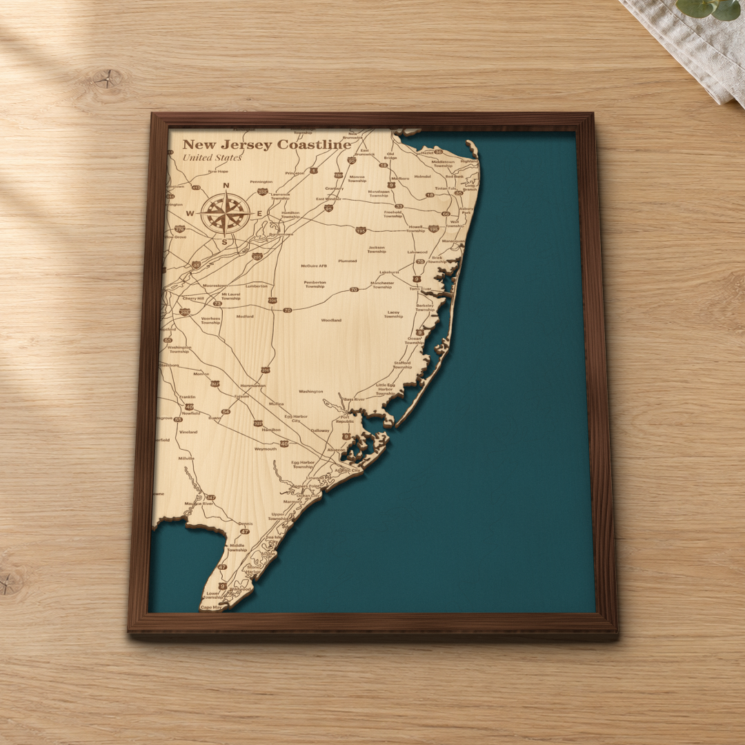 New Jersey Coastline wood map lying flat on a wooden tabletop, showing the ocean depth contours and the Jersey Shore from Long Branch to Cape May engraved in