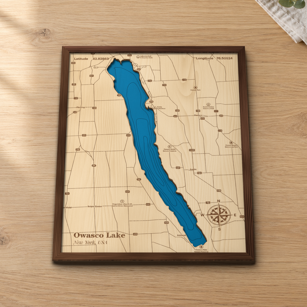 Owasco Lake wood map lying flat on a wooden tabletop, showing the long narrow lake, depth contours and Auburn-area roads