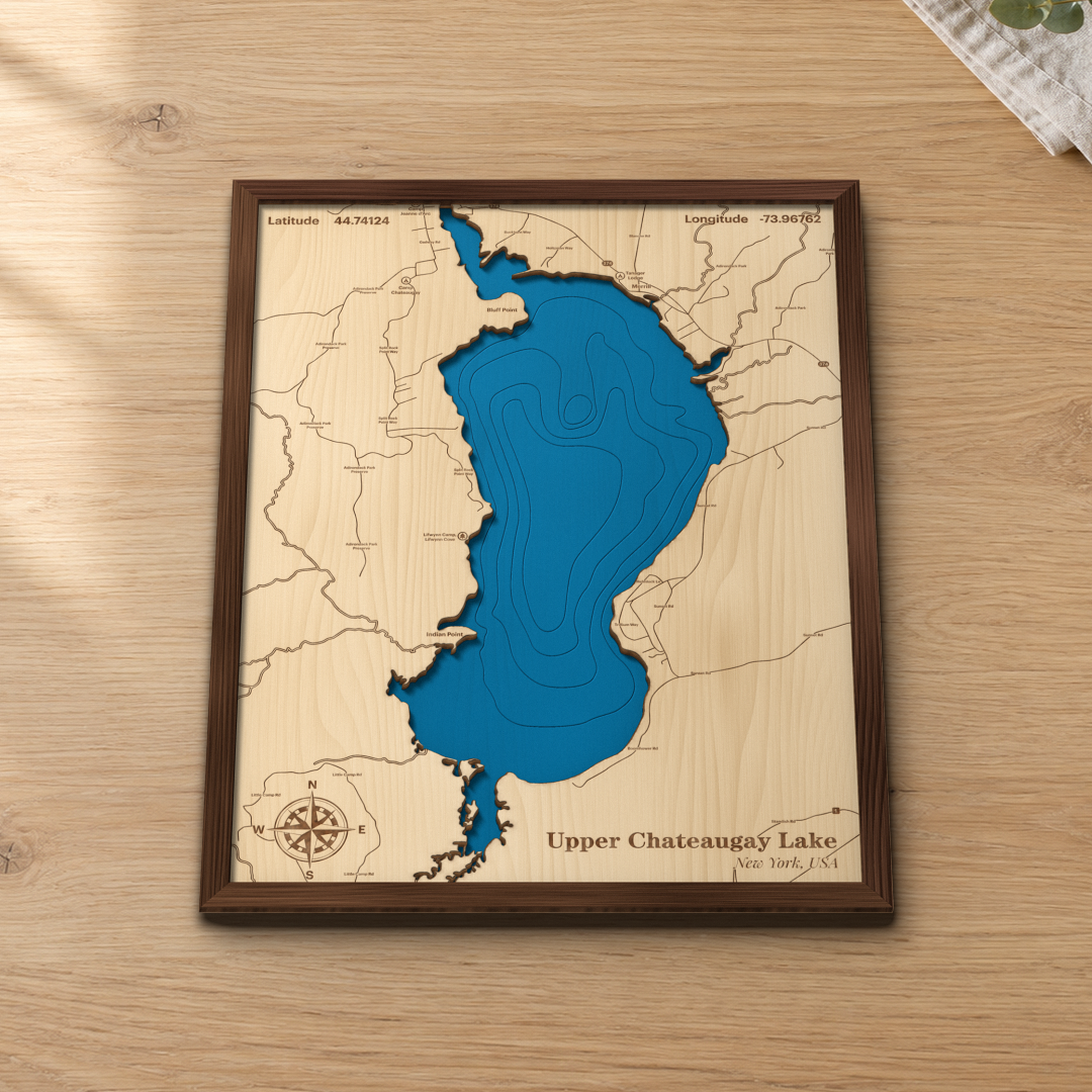 Upper Chateaugay Lake wood map lying flat on a wooden tabletop, showing the lake's depth contours from the Narrows to the south end, with engraved points, camps and roads
