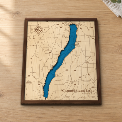 Canandaigua Lake layered wood map in a stained walnut frame lying on a wooden tabletop