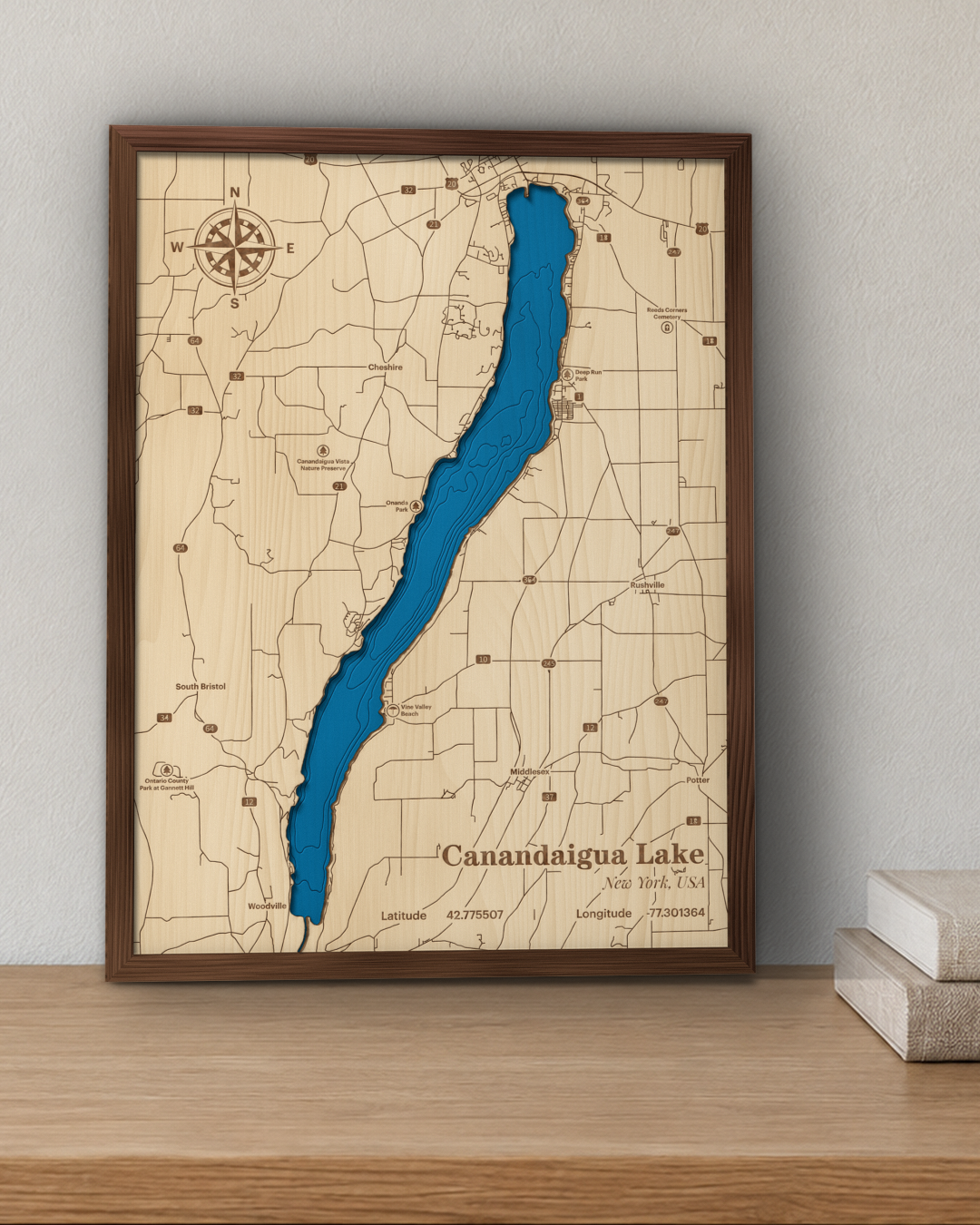 Canandaigua Lake wood map in a stained walnut frame leaning on a wooden shelf in a living room