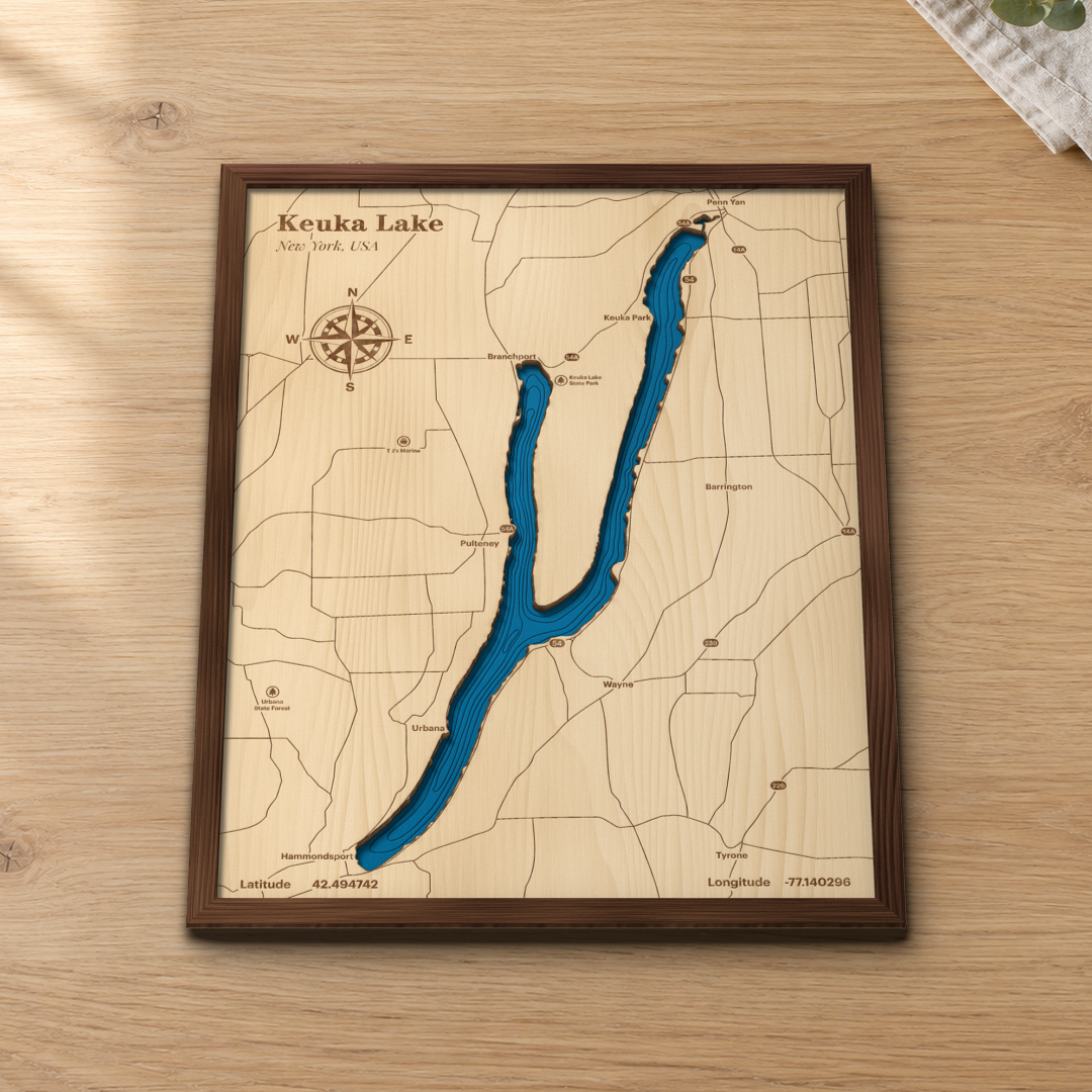 Keuka Lake layered wood map in a stained walnut frame lying on a wooden tabletop