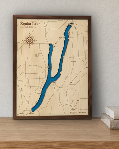 Keuka Lake wood map in a stained walnut frame leaning on a wooden shelf in a living room