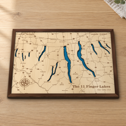 Finger Lakes layered wood map in a stained walnut frame lying on a wooden tabletop