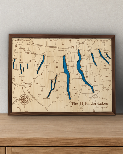 Finger Lakes wood map in a stained walnut frame leaning on a wooden sideboard in a living room