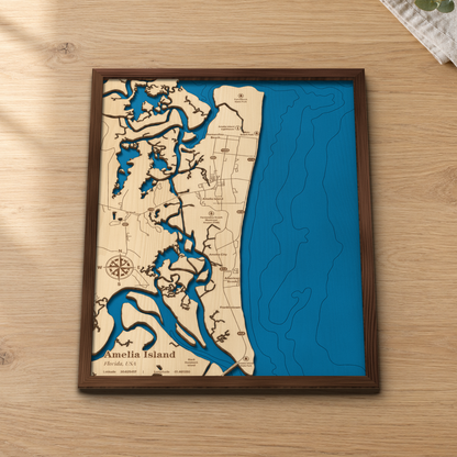 Amelia Island wood map lying flat on a wooden tabletop, showing the ocean depth contours, the marshes and Fernandina Beach engraved in