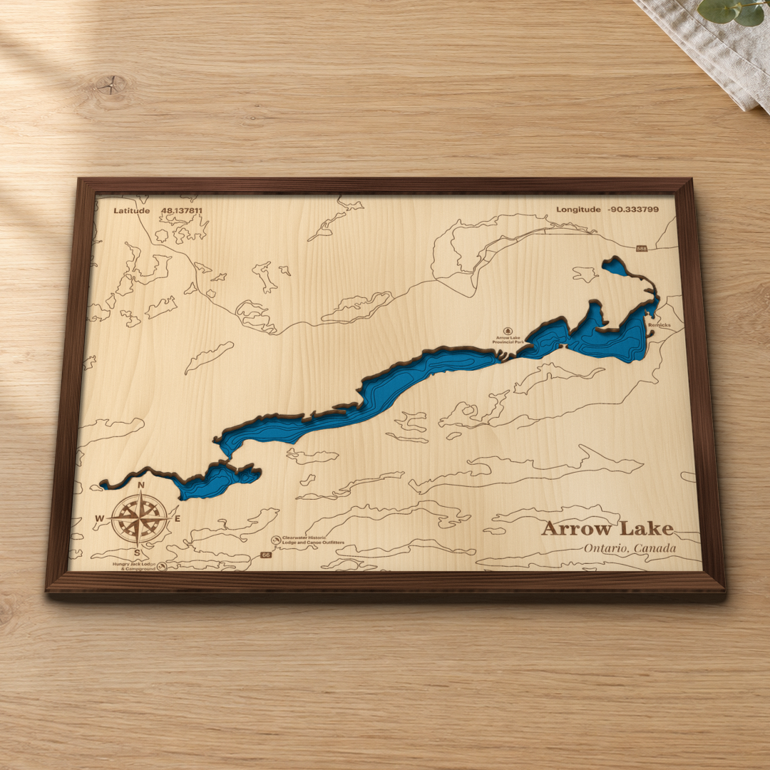 Arrow Lake wood map lying flat on a wooden tabletop, showing the depth contours and the surrounding lakes engraved in