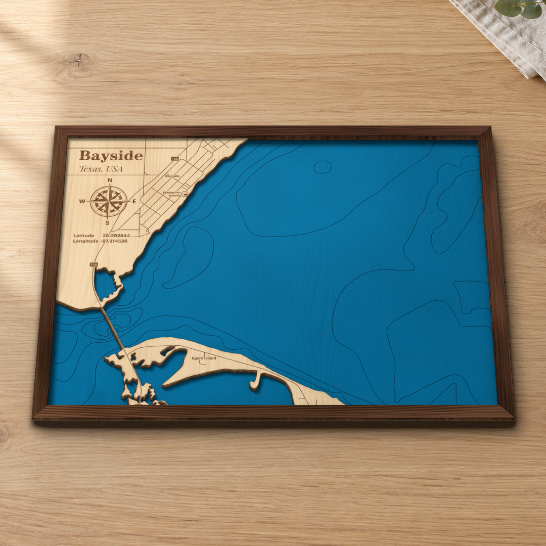 Bayside wood map lying flat on a wooden tabletop, showing the Copano Bay depth contours and the town of Bayside engraved in