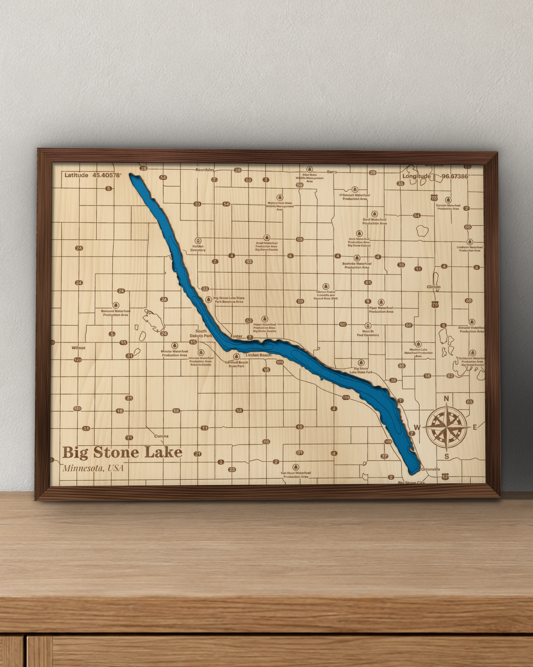 Big Stone Lake wood map in a walnut frame standing on a wooden sideboard against a wall for scale