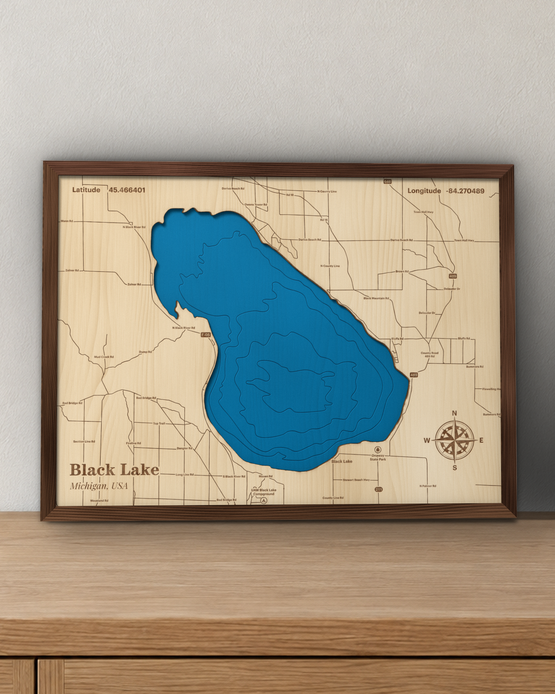 Black Lake wood map in a walnut frame standing on a wooden sideboard against a wall for scale
