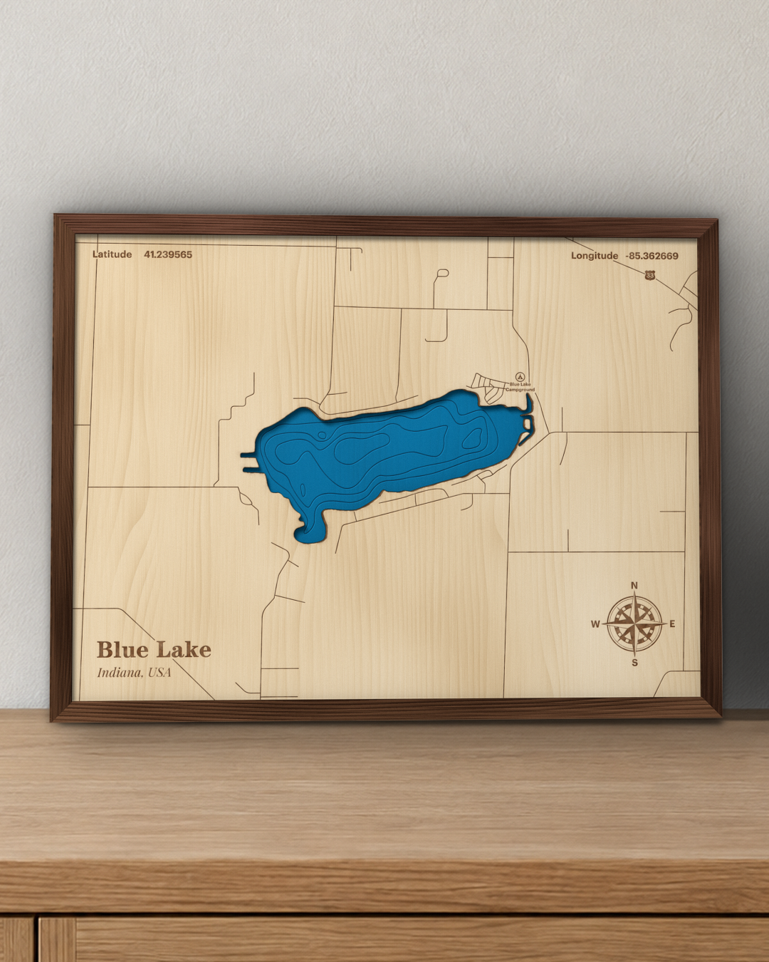 Blue Lake wood map in a walnut frame standing on a wooden sideboard against a wall for scale