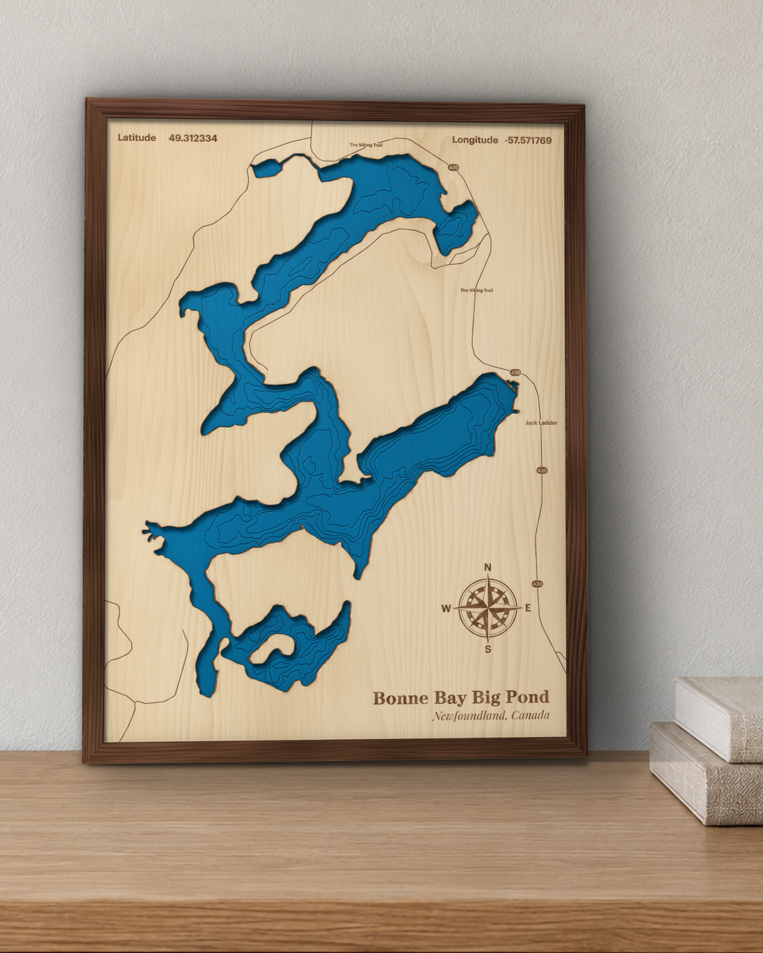 Bonne Bay Big Pond wood map in a walnut frame standing on a wooden sideboard against a wall for scale