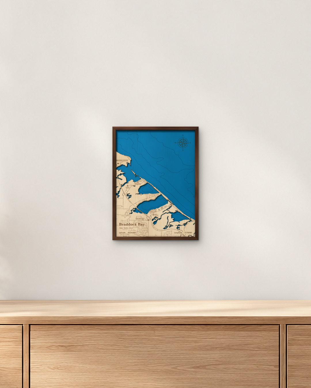 Braddock Bay wood map in a walnut frame hanging on a wall above a wooden sideboard
