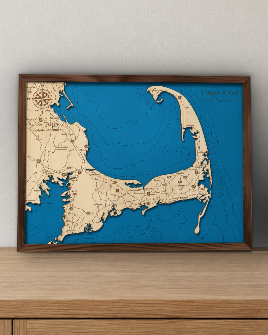 Cape Cod Bay wood map in a walnut frame standing on a wooden sideboard against a wall for scale