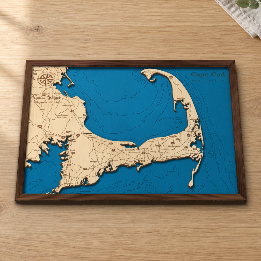 Cape Cod Bay wood map lying flat on a wooden tabletop, showing the Cape Cod Bay and Atlantic depth contours engraved in