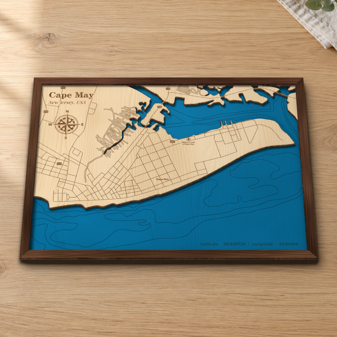 Cape May wood map lying flat on a wooden tabletop, showing the Atlantic depth contours off the Cape May beachfront engraved in