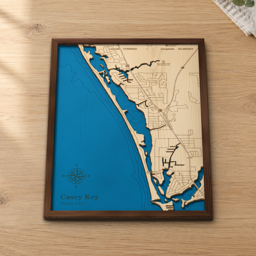 Casey Key wood map lying flat on a wooden tabletop, showing the Gulf of Mexico depth contours and Little Sarasota Bay engraved in