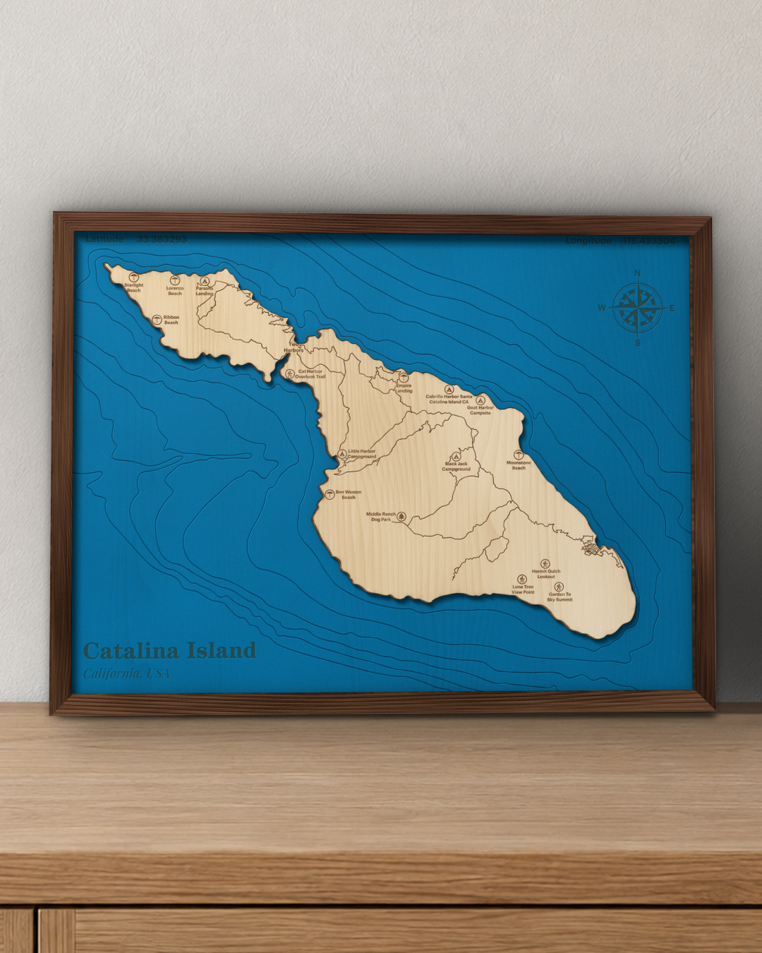 Catalina Island wood map in a walnut frame standing on a wooden sideboard against a wall for scale