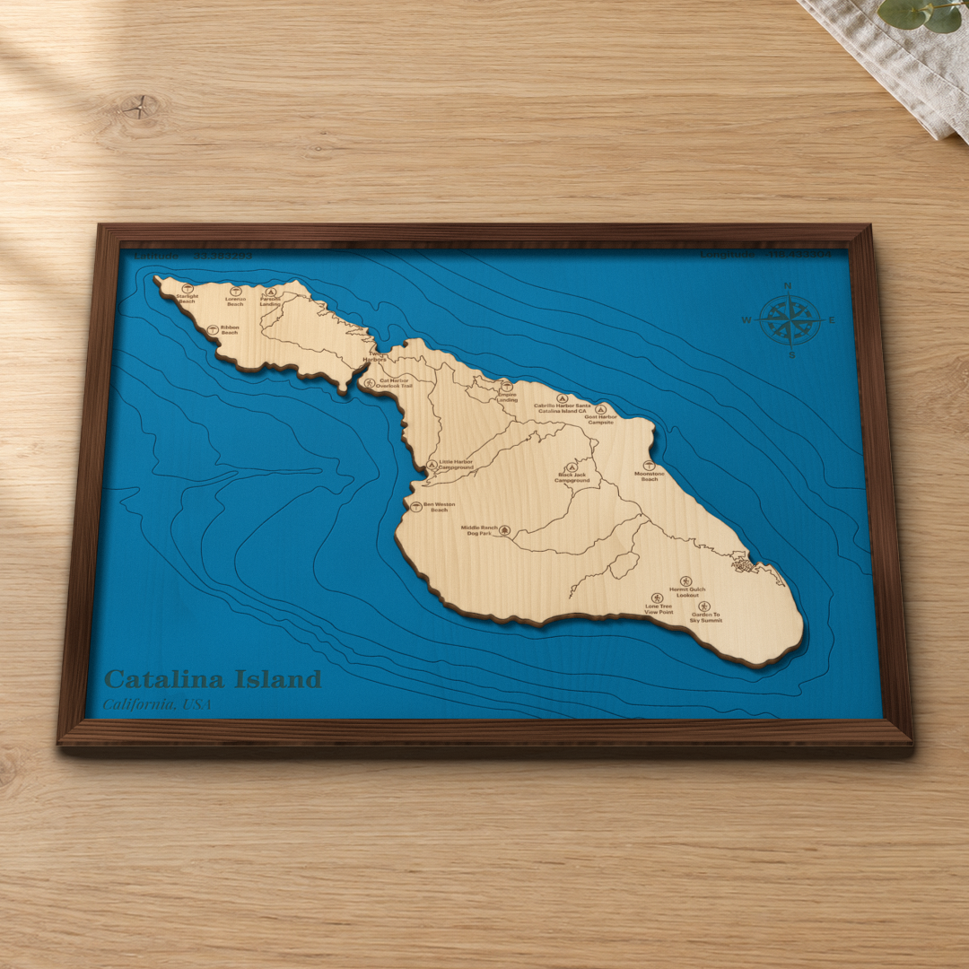 Catalina Island wood map lying flat on a wooden tabletop, showing the depth contours around the island, Avalon and Two Harbors engraved in
