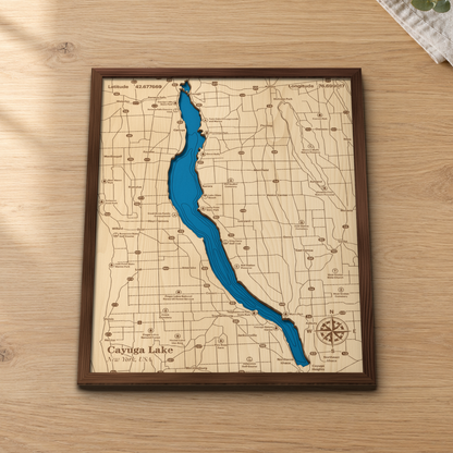Cayuga Lake wood map lying flat on a wooden tabletop, showing the whole lake's depth contours, with engraved towns, parks and highways from Seneca Falls to Cayuga Heights