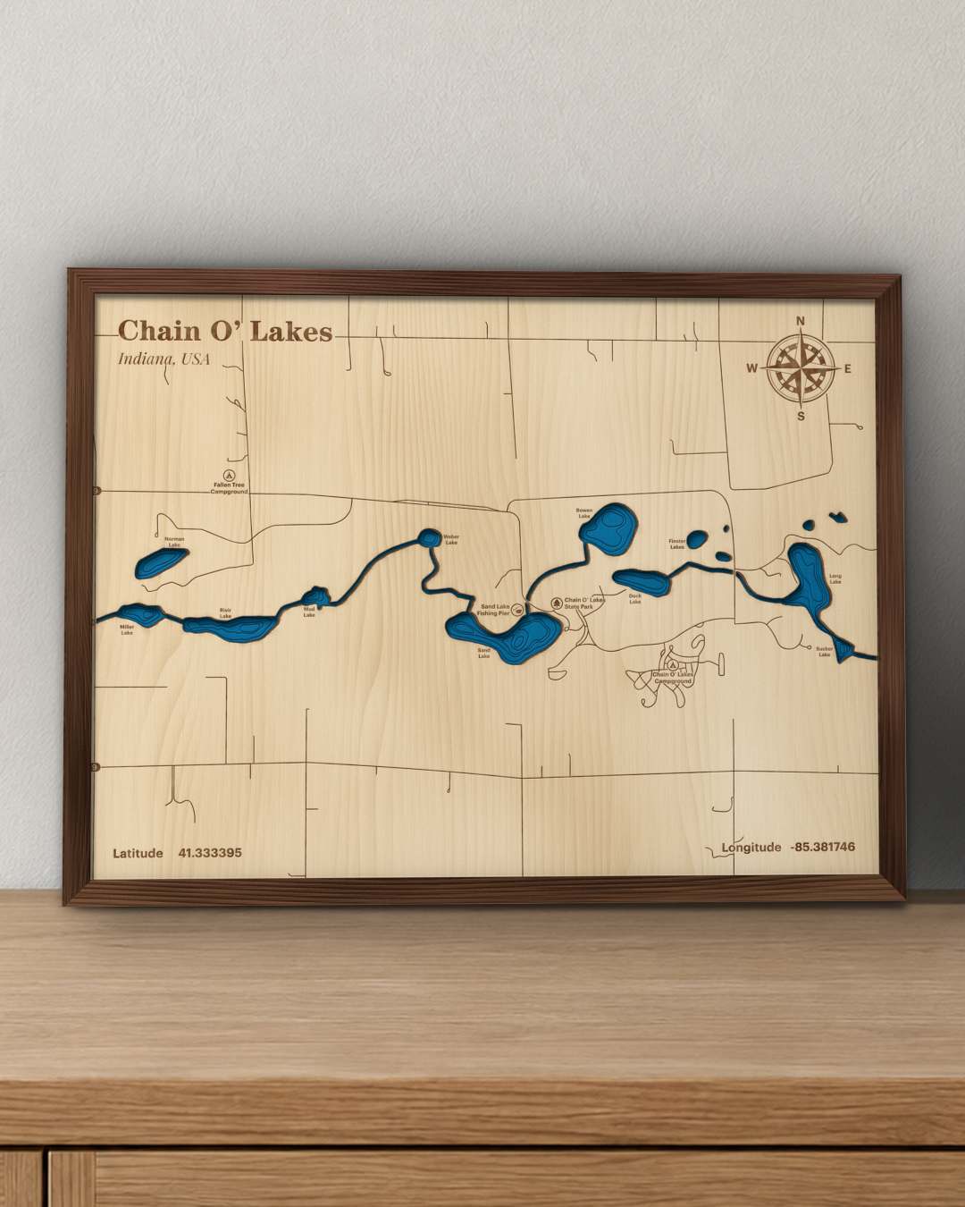 Chain O' Lakes wood map in a walnut frame standing on a wooden sideboard against a wall for scale