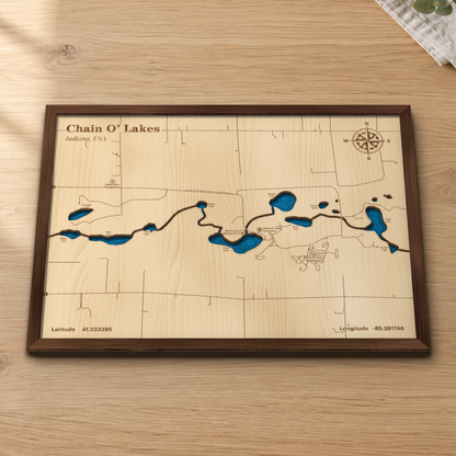 Chain O' Lakes wood map lying flat on a wooden tabletop, showing the nine connected kettle lakes and their depth contours engraved in