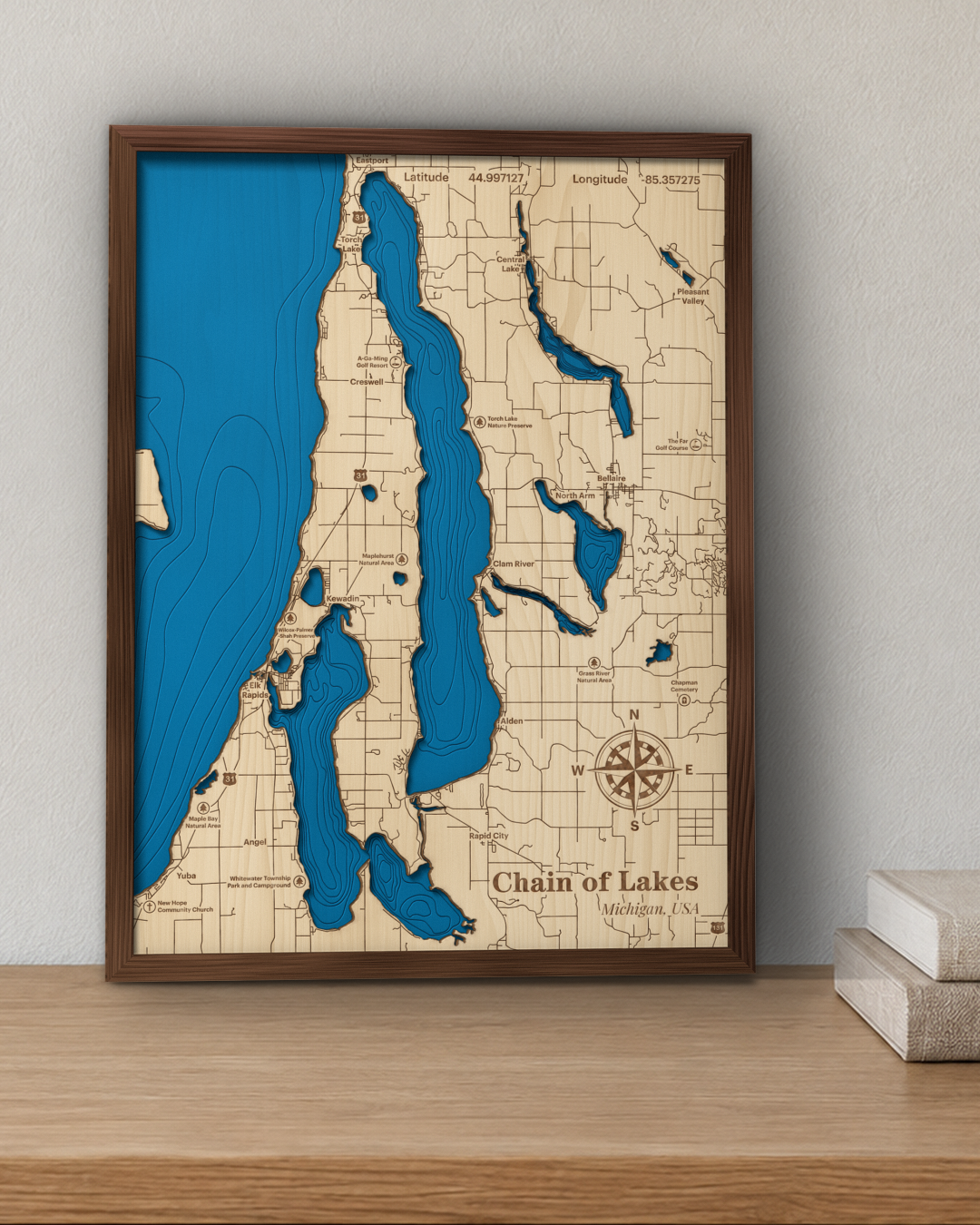 Chain of Lakes wood map in a walnut frame standing on a wooden sideboard against a wall for scale