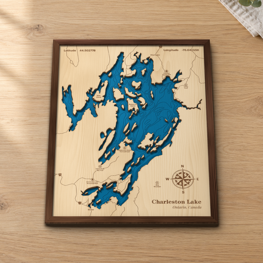 Charleston Lake wood map lying flat on a wooden tabletop, showing the depth contours, the islands and the bays engraved in