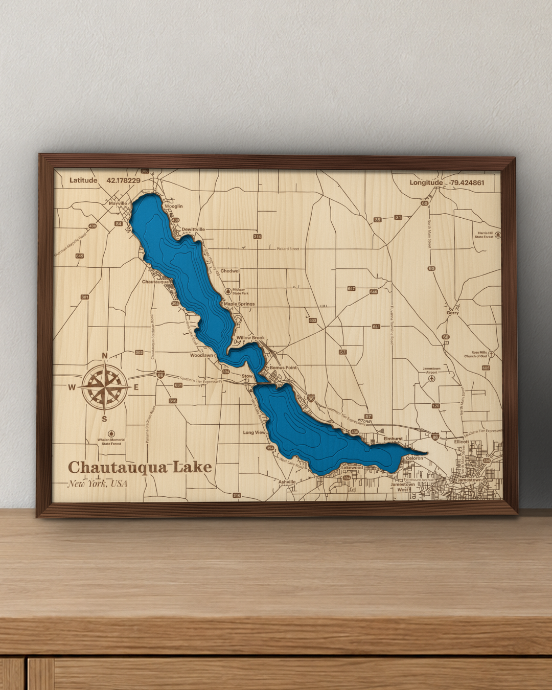 Chautauqua Lake wood map in a walnut frame standing on a wooden sideboard against a wall for scale