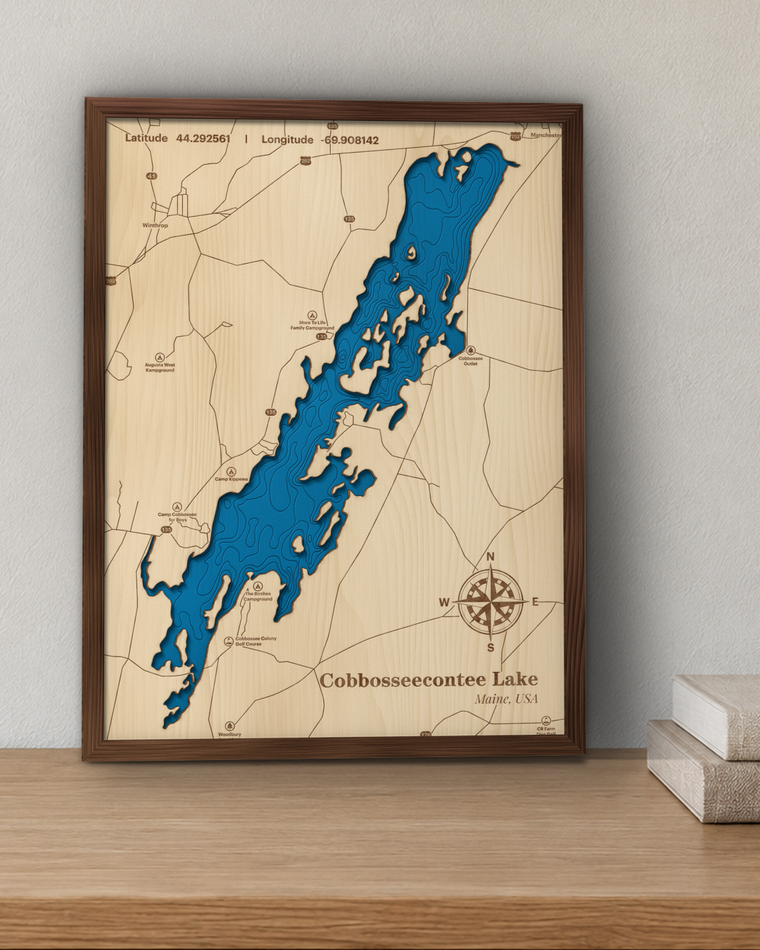 Cobbosseecontee Lake wood map in a walnut frame standing on a wooden sideboard against a wall for scale
