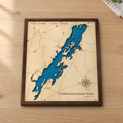 Cobbosseecontee Lake wood map lying flat on a wooden tabletop, showing the depth contours and islands engraved in