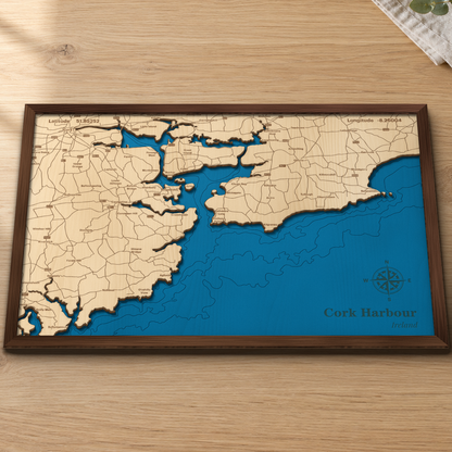 Cork Harbour wood map lying flat on a wooden tabletop, showing the harbour and Celtic Sea depth contours engraved in