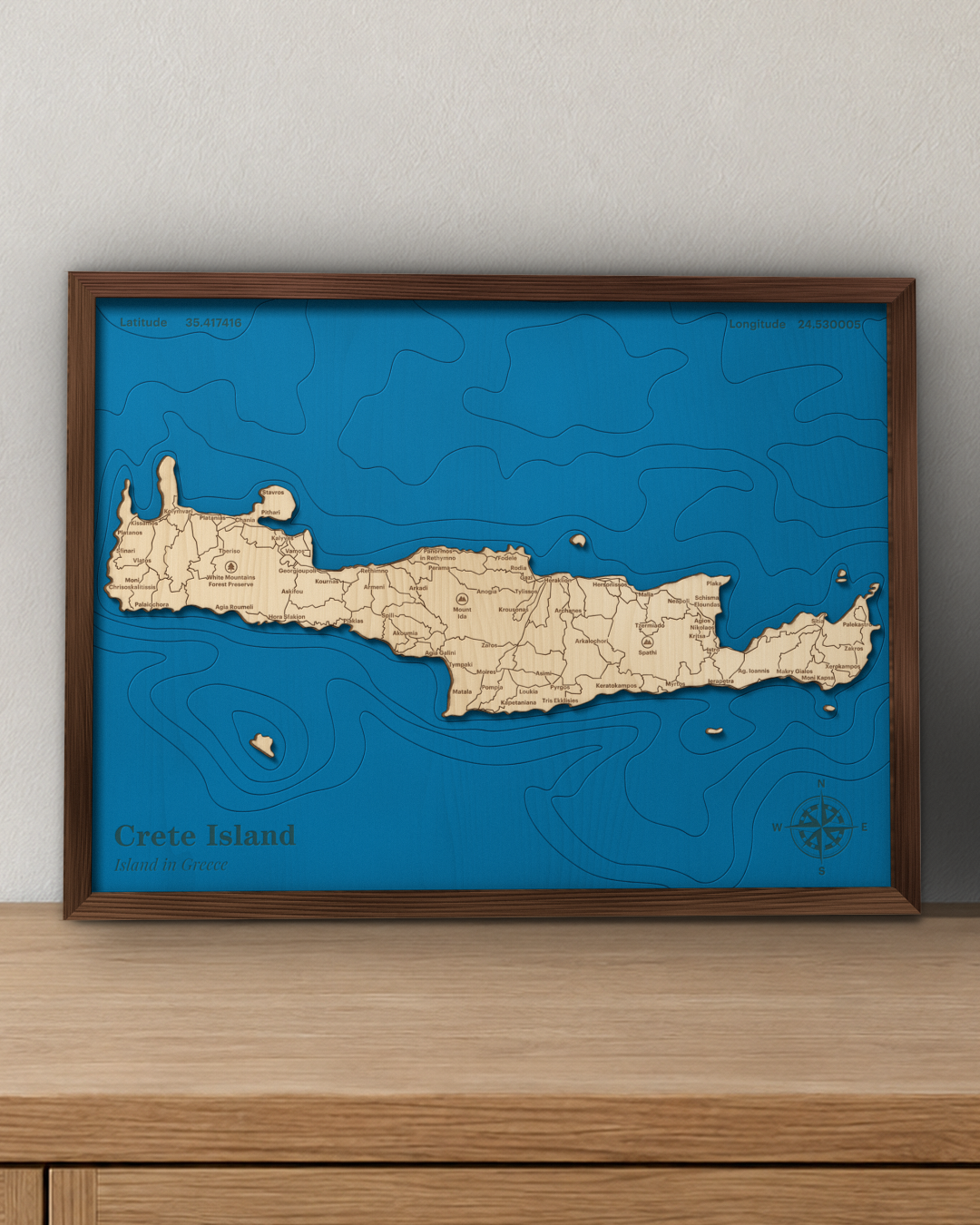 Crete wood map in a walnut frame standing on a wooden sideboard against a wall for scale