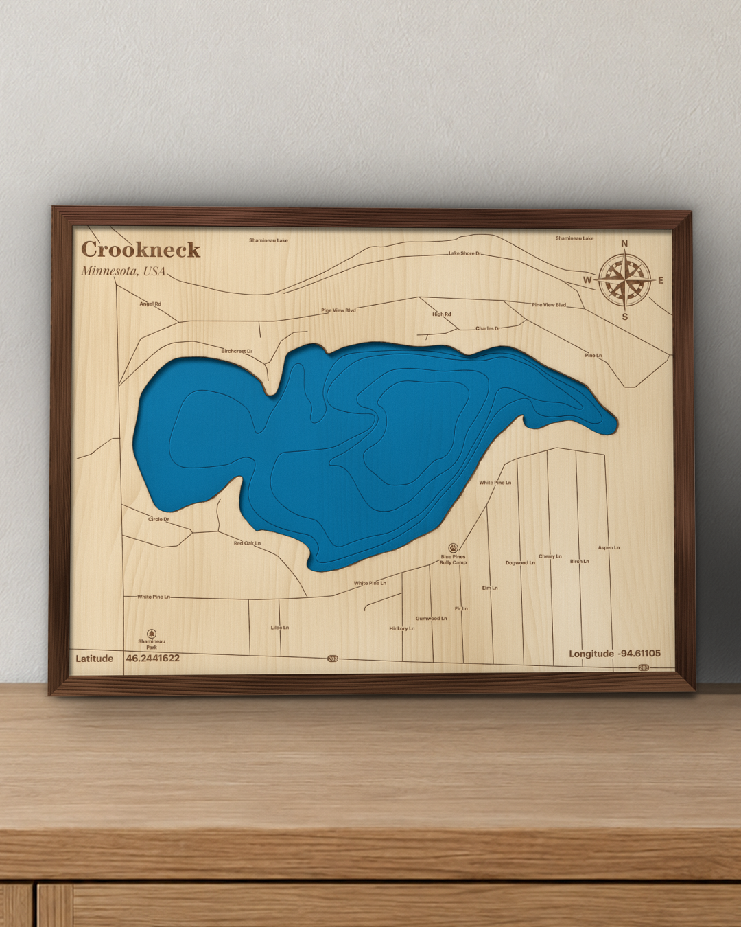 Crookneck Lake wood map in a walnut frame standing on a wooden sideboard against a wall for scale