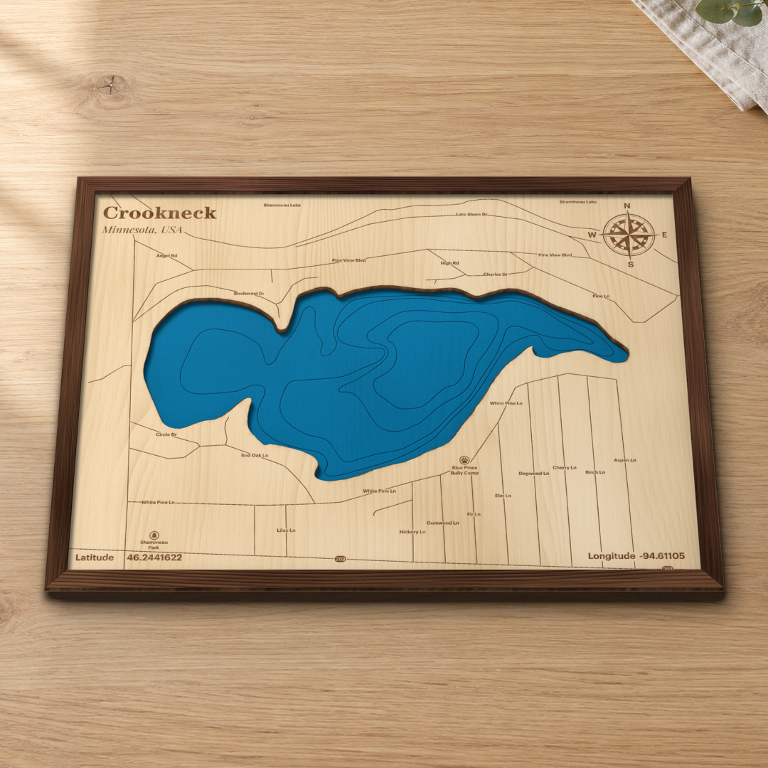 Crookneck Lake wood map lying flat on a wooden tabletop, showing the depth contours and the lake roads engraved in