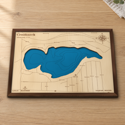 Crookneck Lake wood map lying flat on a wooden tabletop, showing the depth contours and the lake roads engraved in