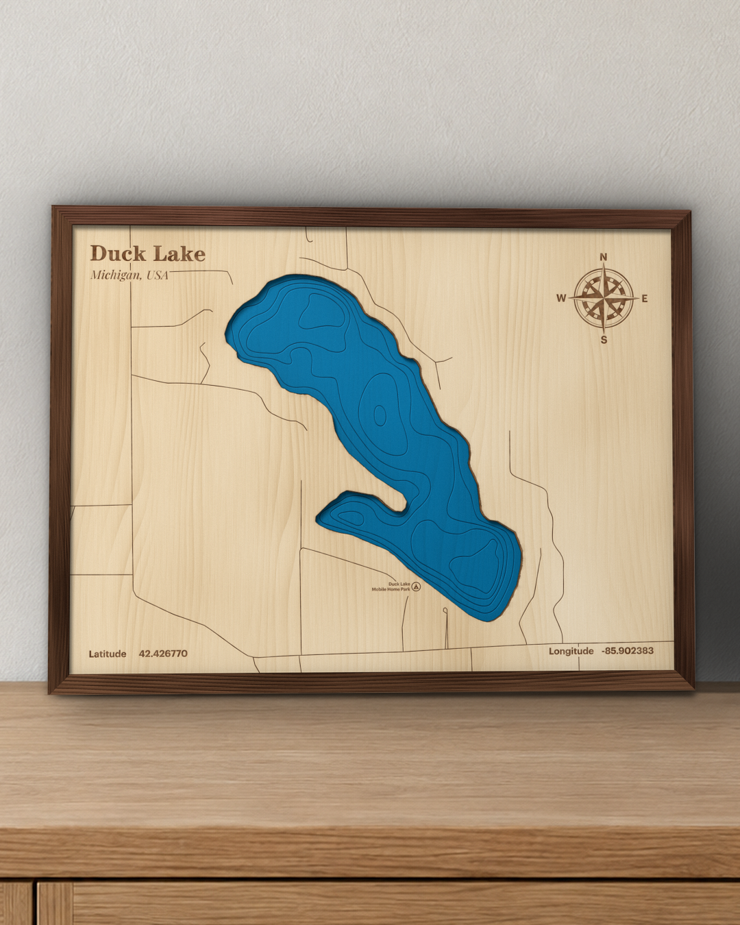 Duck Lake wood map in a walnut frame standing on a wooden sideboard against a wall for scale