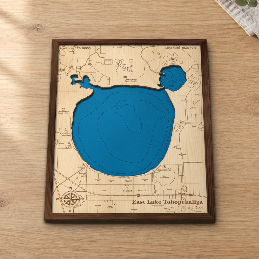 East Lake Tohopekaliga wood map lying flat on a wooden tabletop, showing the lake's depth contours with St. Cloud, Narcoossee and the Lakefront Beach engraved in