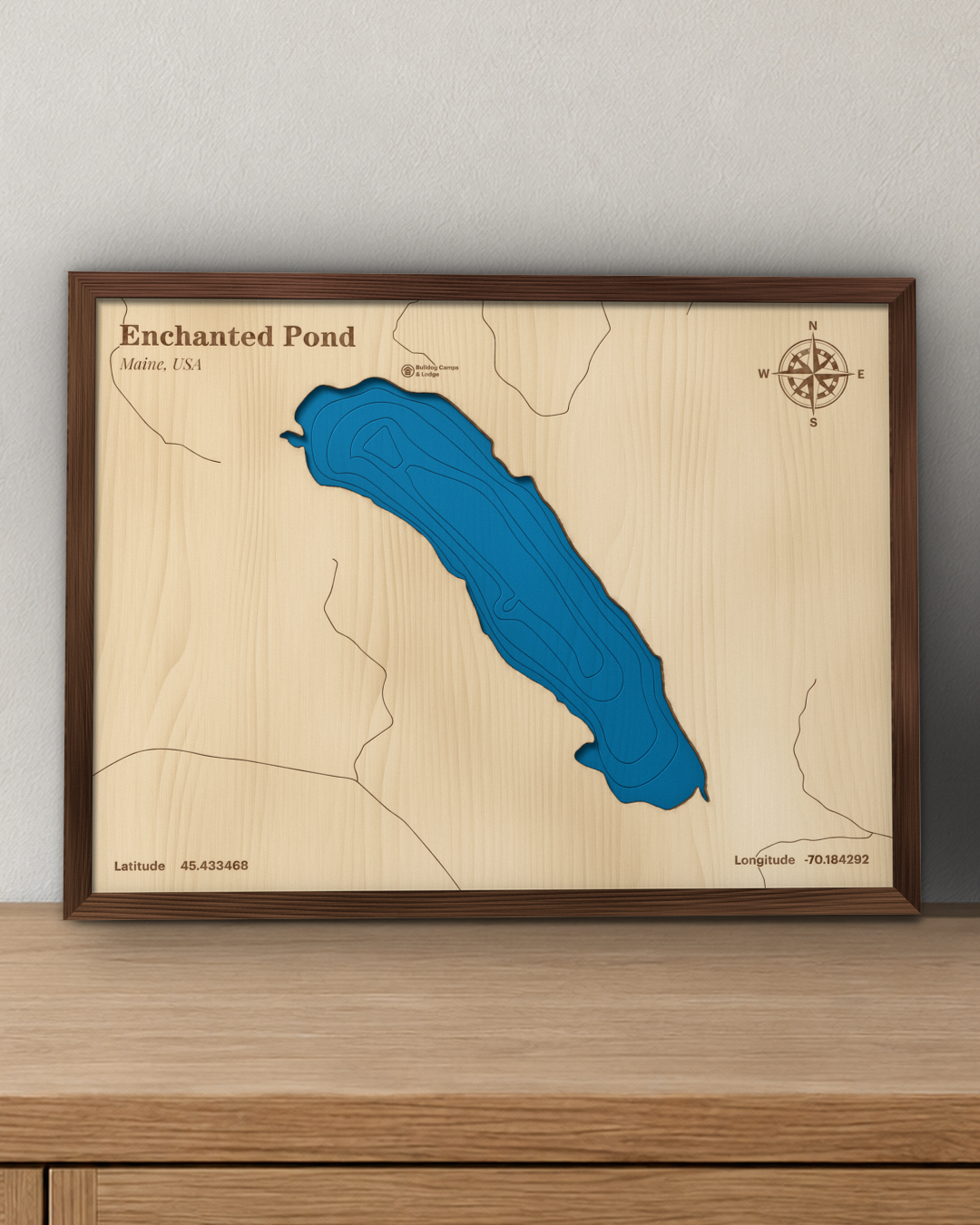 Enchanted Pond wood map in a walnut frame standing on a wooden sideboard against a wall for scale