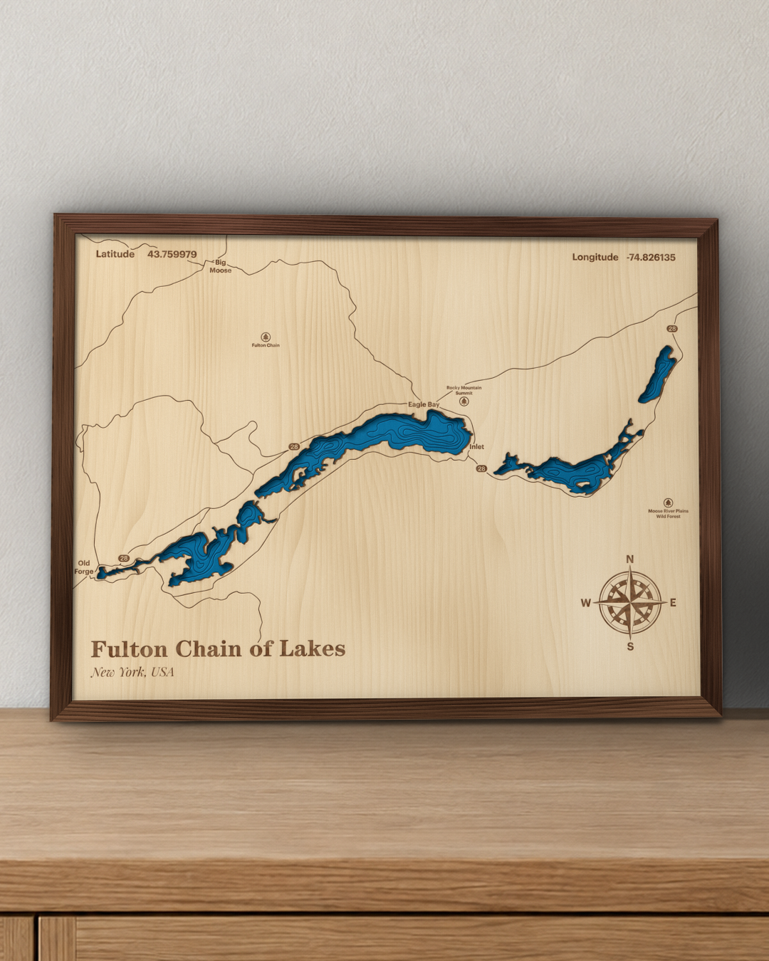 Fulton Chain of Lakes wood map in a walnut frame standing on a wooden sideboard against a wall for scale