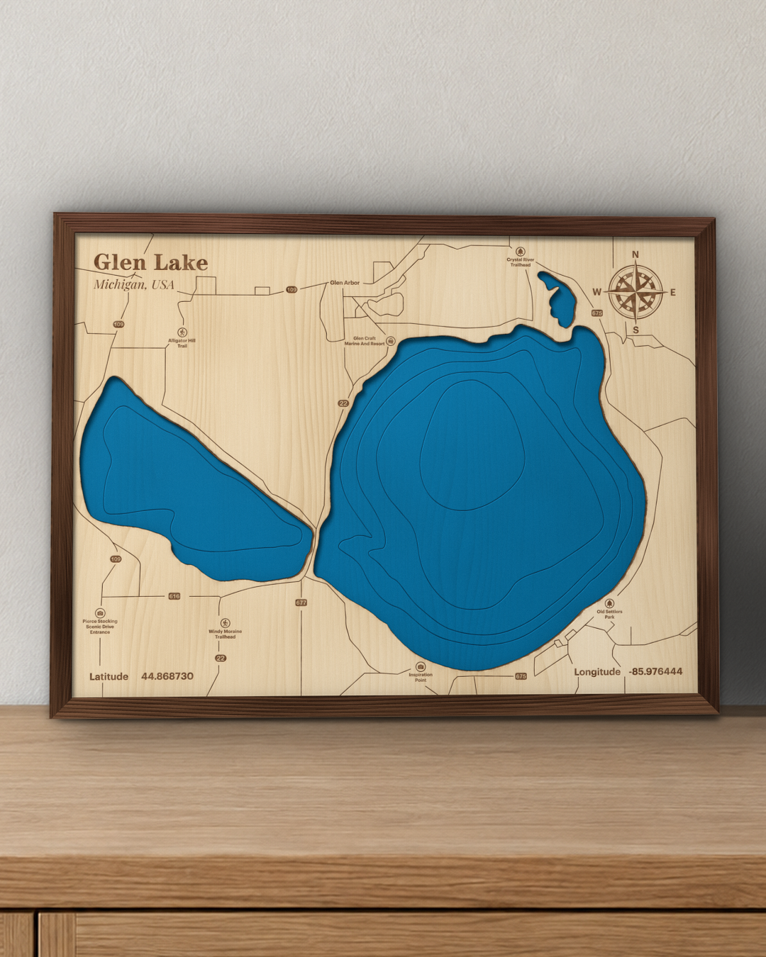 Glen Lake wood map in a walnut frame standing on a wooden sideboard against a wall for scale