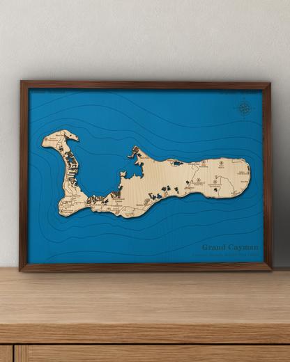 Grand Cayman wood map in a walnut frame standing on a wooden sideboard against a wall for scale