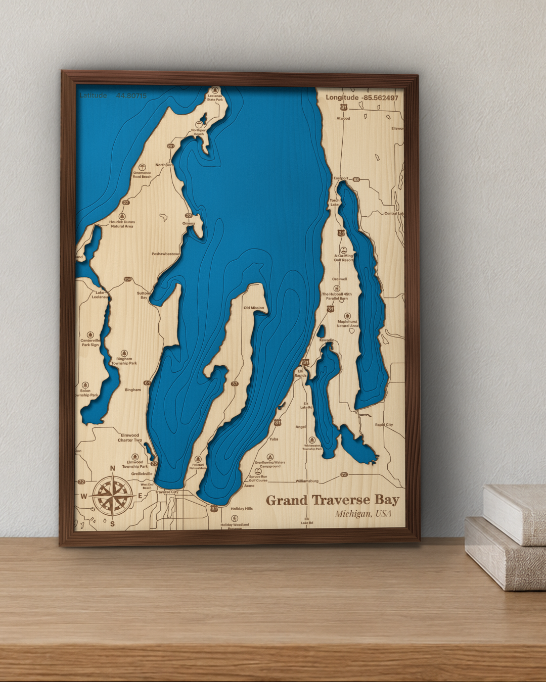 Grand Traverse Bay wood map in a walnut frame standing on a wooden sideboard against a wall for scale