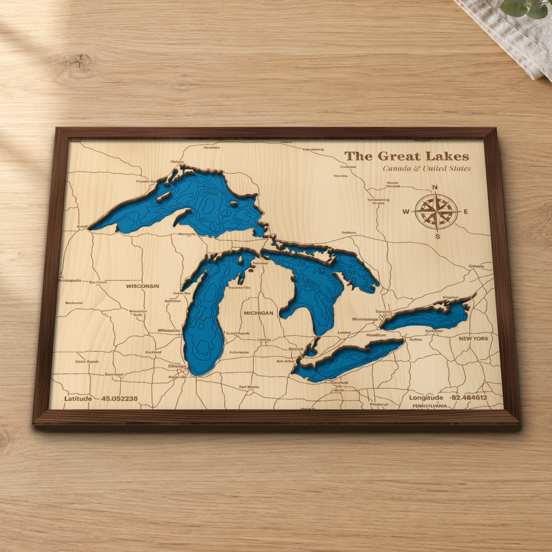 Great Lakes wood map lying flat on a wooden tabletop, showing all five lakes with depth contours and engraved cities and highways