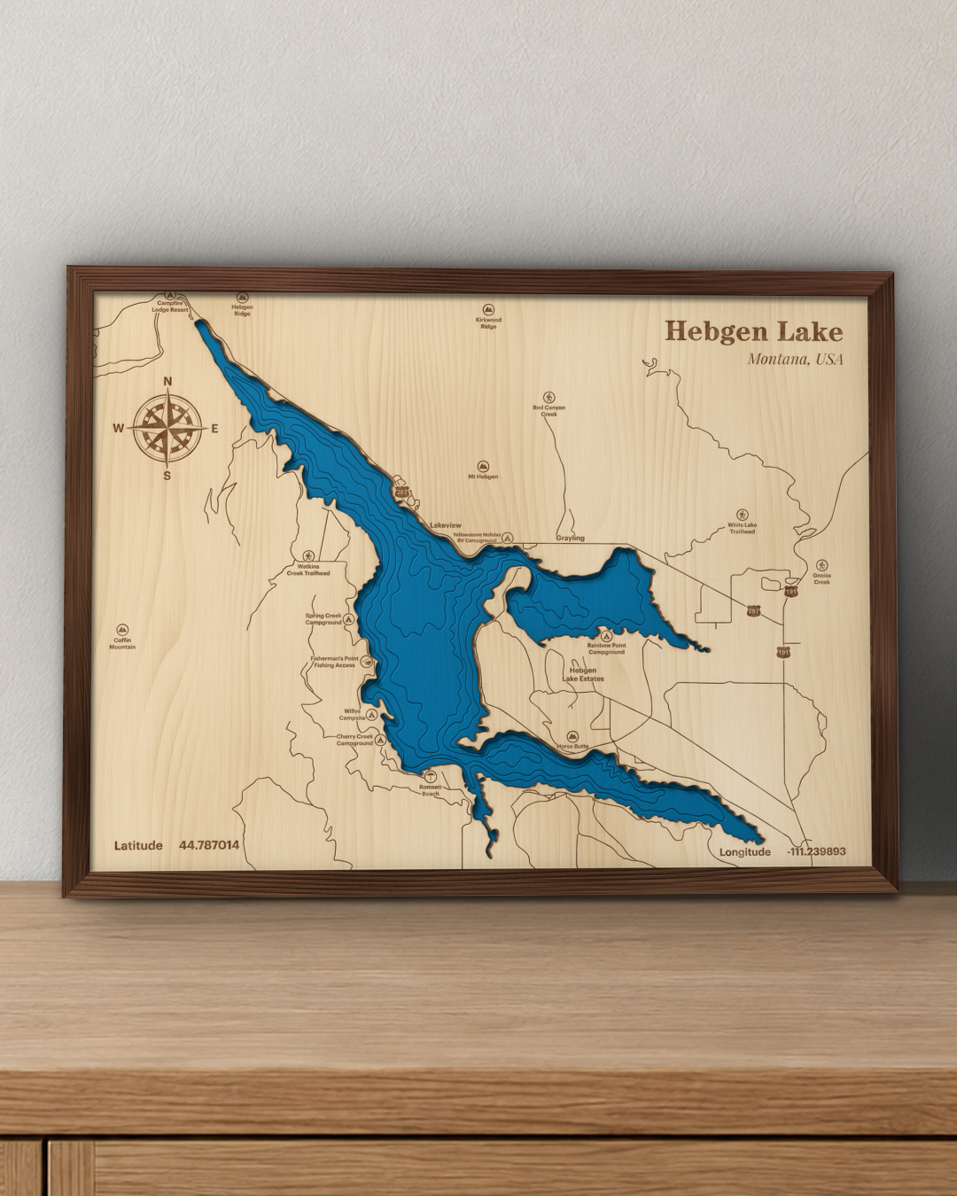 Hebgen Lake wood map in a walnut frame standing on a wooden sideboard against a wall for scale